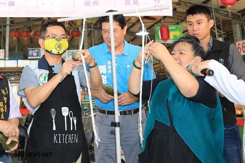 宜蘭市長江聰淵今天也在記者會場學習如何包粽、綁粽。